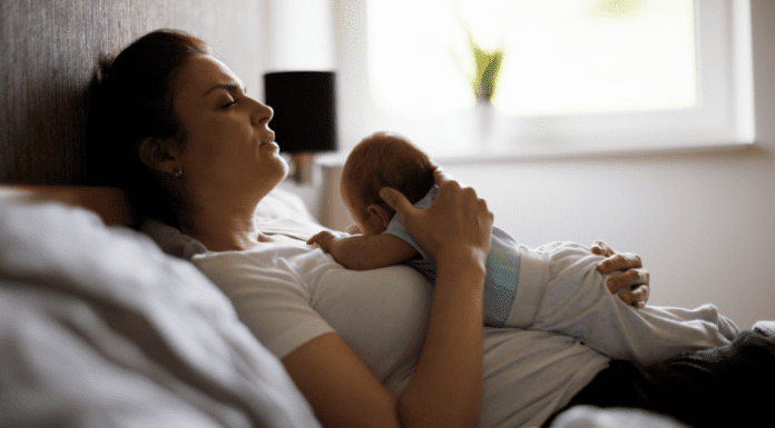 A mom postpartum holding her baby in bed.