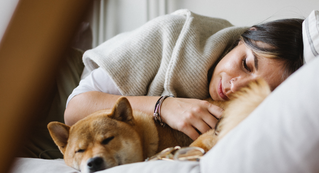 A woman laying down with her dog. 