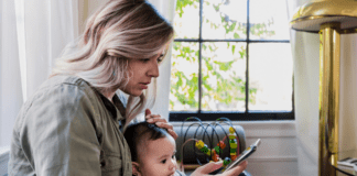 Becoming a Mom in the Age of Social Media A new mom checking social media while holding her baby.
