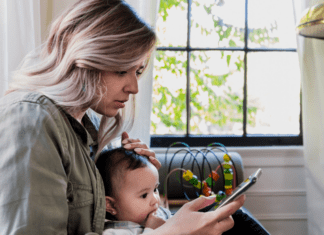 A new mom checking social media while holding her baby.