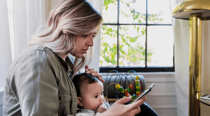 Becoming a Mom in the Age of Social Media A new mom checking social media while holding her baby.