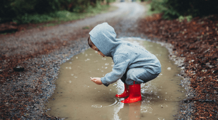 A boy playing in a giant puddle.