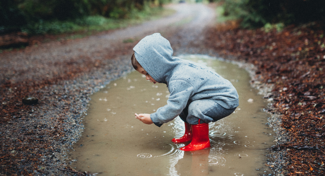 A boy playing in a giant puddle. 