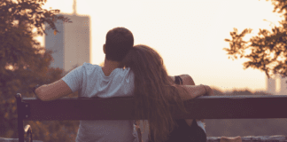A couple cuddling together on a park bench.
