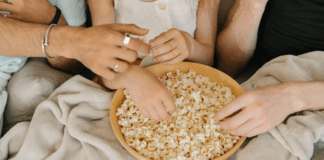 Popcorn Lovers Day Hands reaching for a bowl of popcorn.