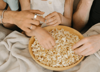 Popcorn Lovers Day Hands reaching for a bowl of popcorn.