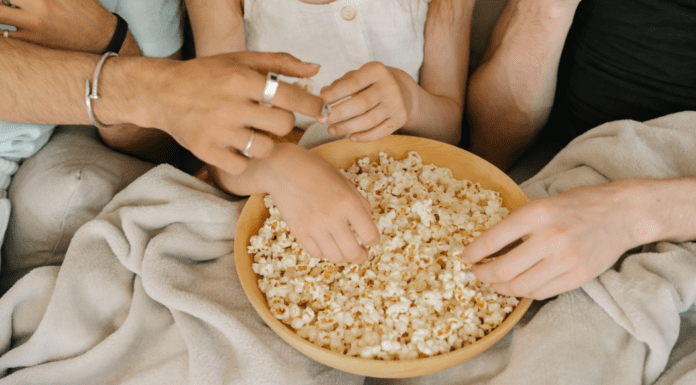 Popcorn Lovers Day Hands reaching for a bowl of popcorn.