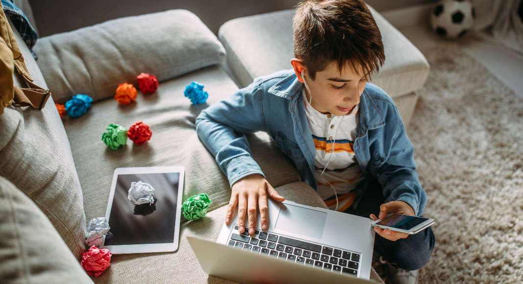 A boy on his computer and phone.