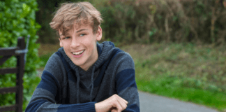 A boy leaning on a fence.