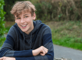 A boy leaning on a fence.