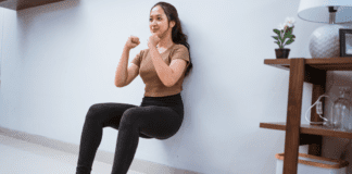 Get Fit Without a Gym A woman doing a wall-sit to get fit without the gym.