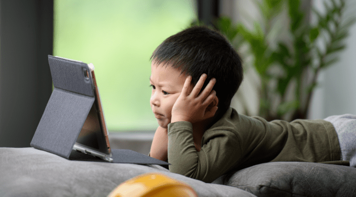 Beyond the Screen: The Neuropsychology of Digital Device Impact on Developing Brains A kid glued to his tablet with too much screen time.