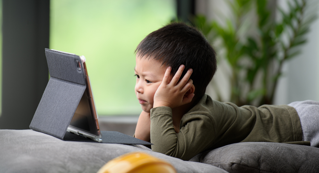 A kid glued to his tablet with too much screen time.