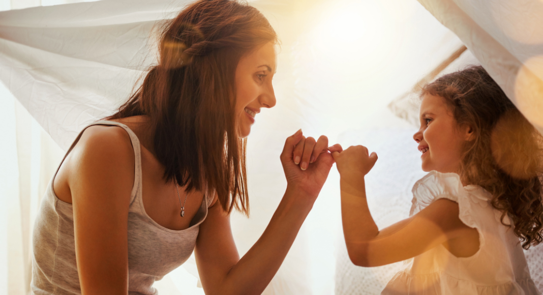 A mom making a pinky promise with her daughter.