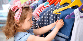 15 Tips to Save Money on Fall Fashions for Back-to-School A girl looking through a rack of clothes.