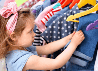 15 Tips to Save Money on Fall Fashions for Back-to-School A girl looking through a rack of clothes.