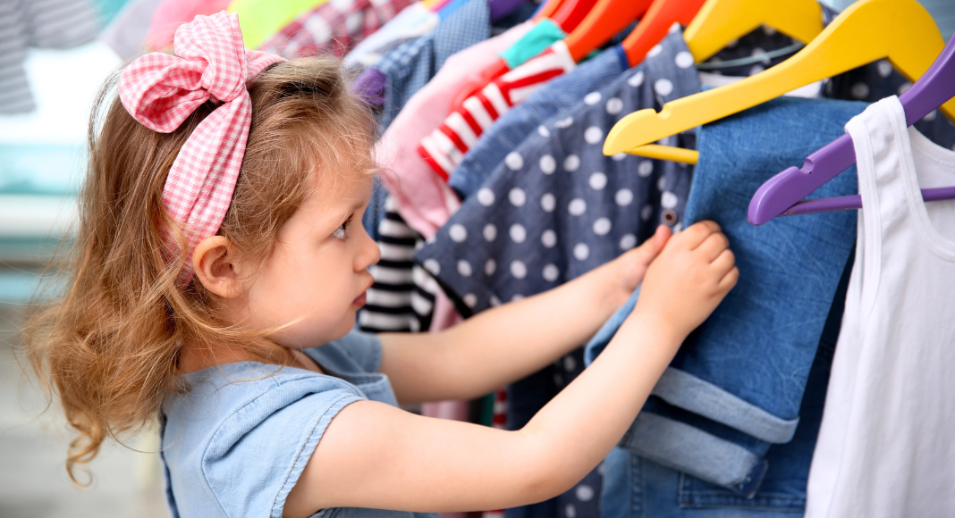A girl looking through a rack of clothes.