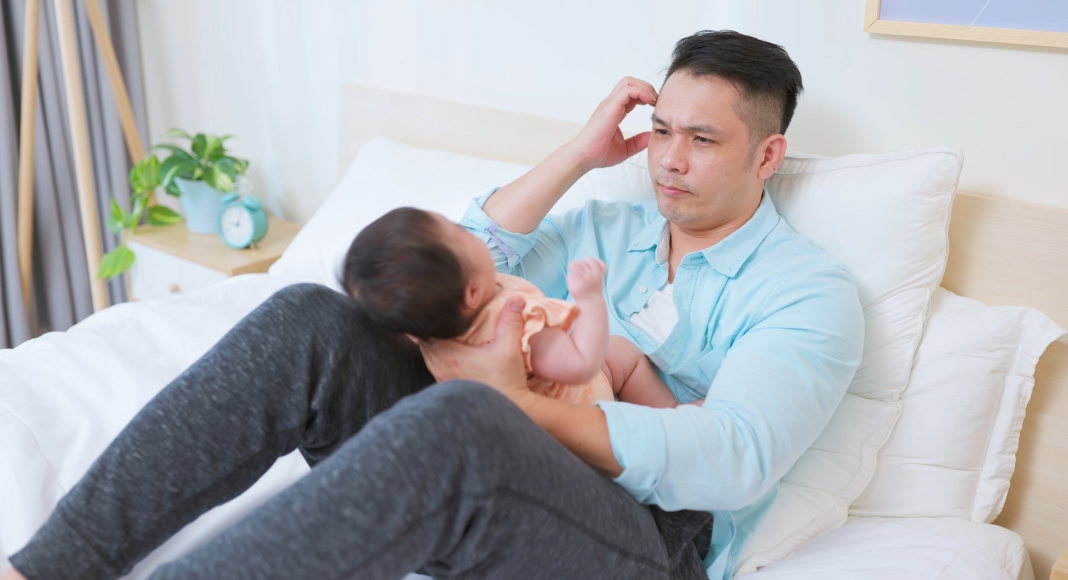 A father struggling holding a baby.