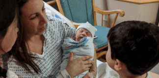 Teaching Empathy A mom holding a newborn for her children to see.