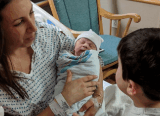 A mom holding a newborn for her children to see.