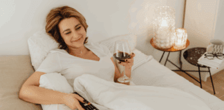 Binge-Worthy TV Shows to Watch A woman holding a tv remote and glass of wine.