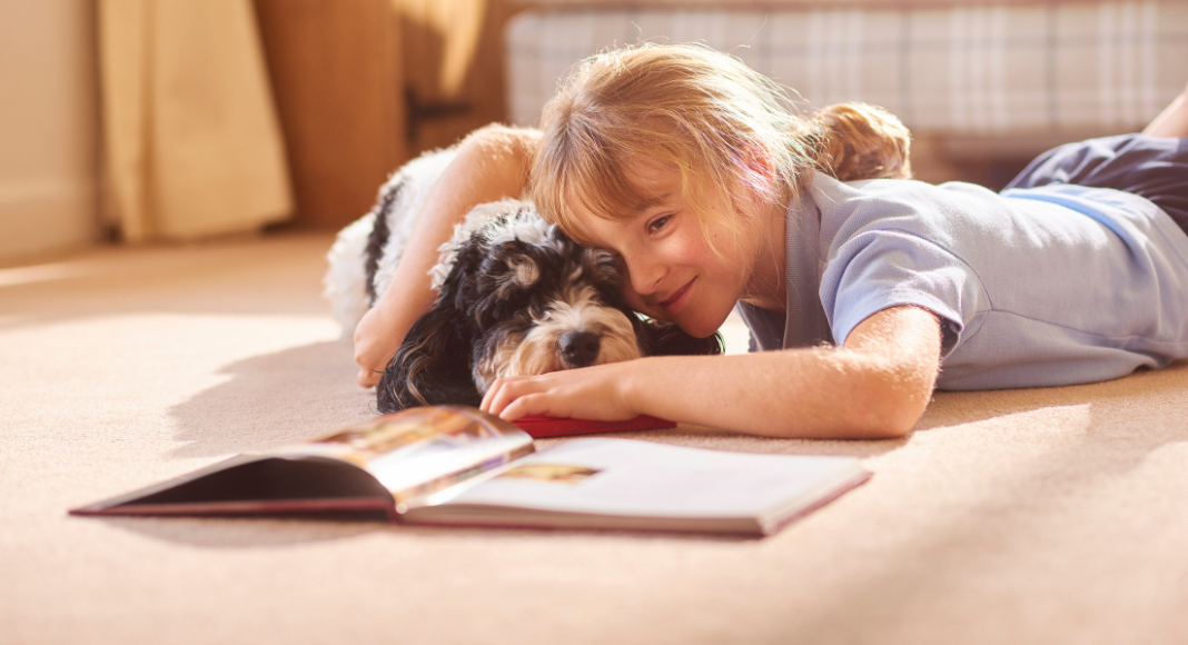A girl reading a book to her dog. 