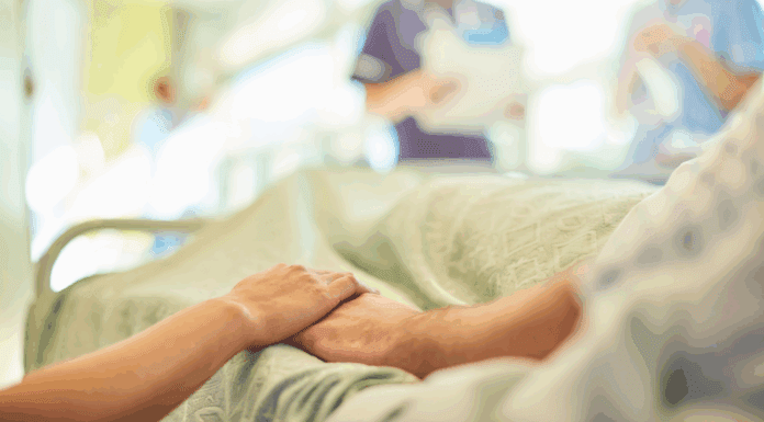 People holding hands in a hospital bed.