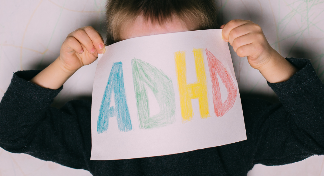 A child holding a sign that says "ADHD."