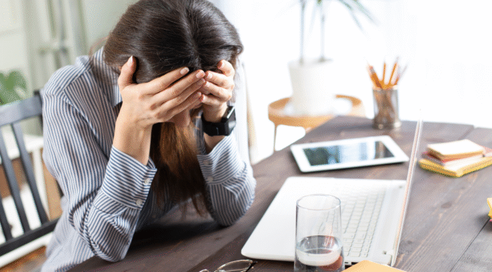 A woman holding her head in front of her computer.