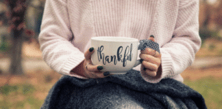 Hands holding a mug that says thankful.
