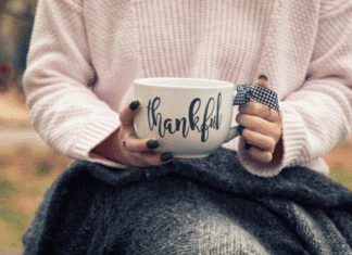 Hands holding a mug that says thankful.