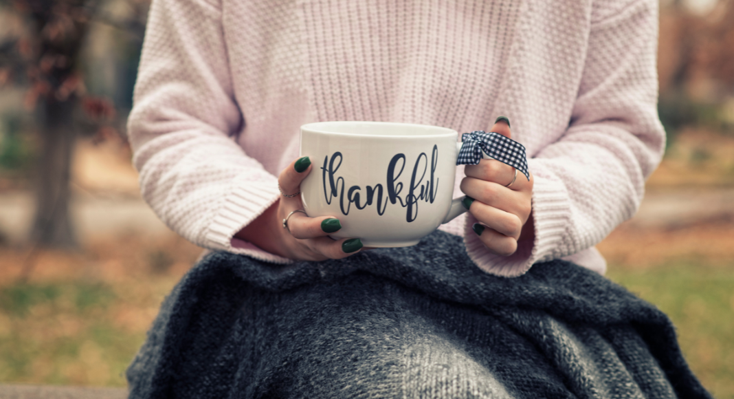 Hands holding a mug that says thankful. 
