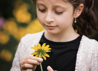 A girl looking at a flower.