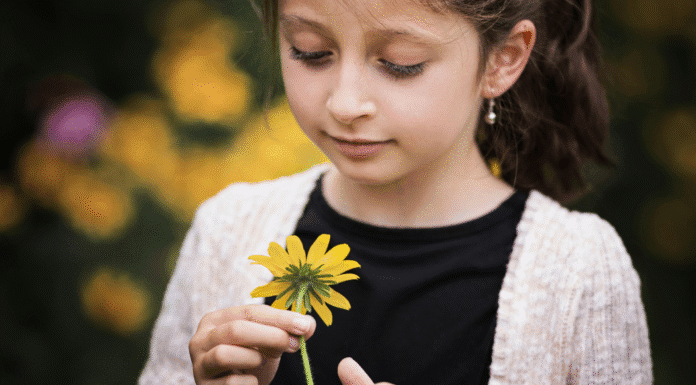 A girl looking at a flower.
