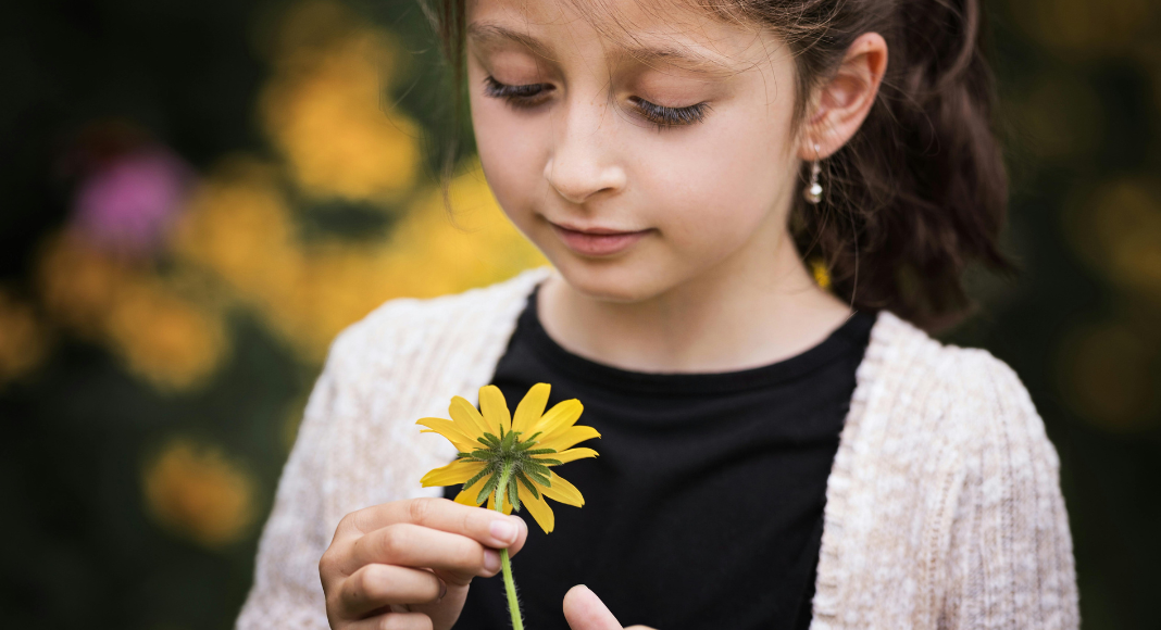 A girl looking at a flower.