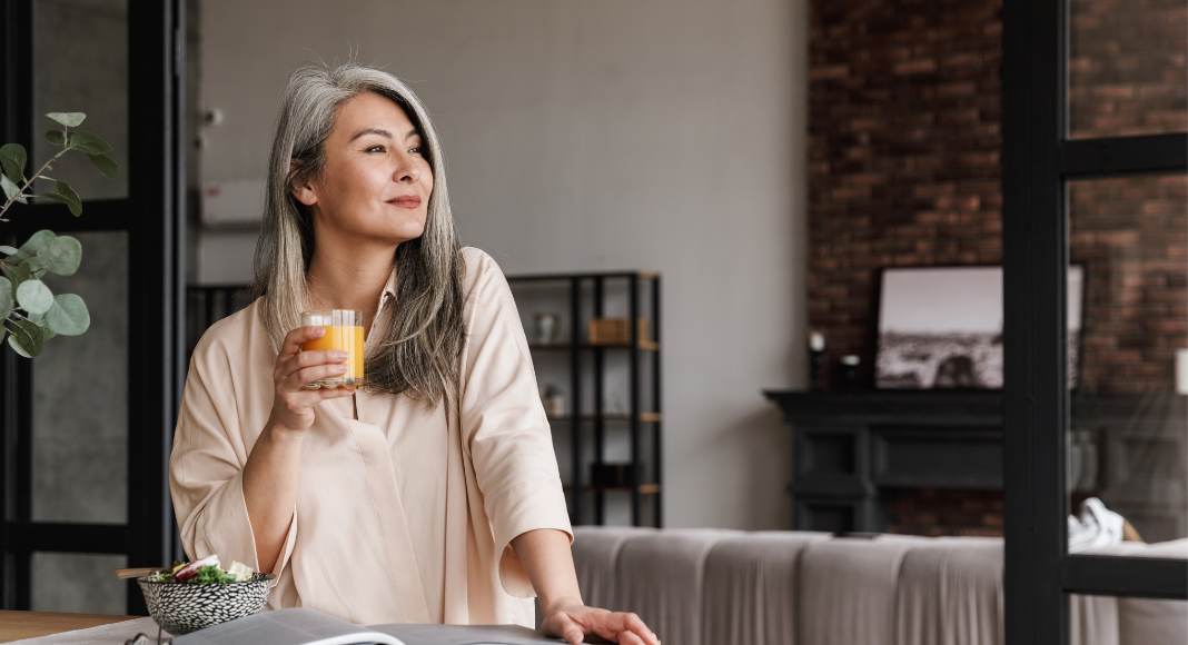 A woman drinking a glass of orange juice.