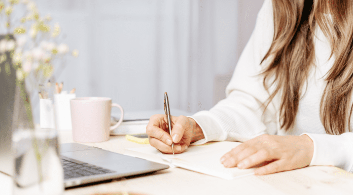 A woman sitting down to write a book.