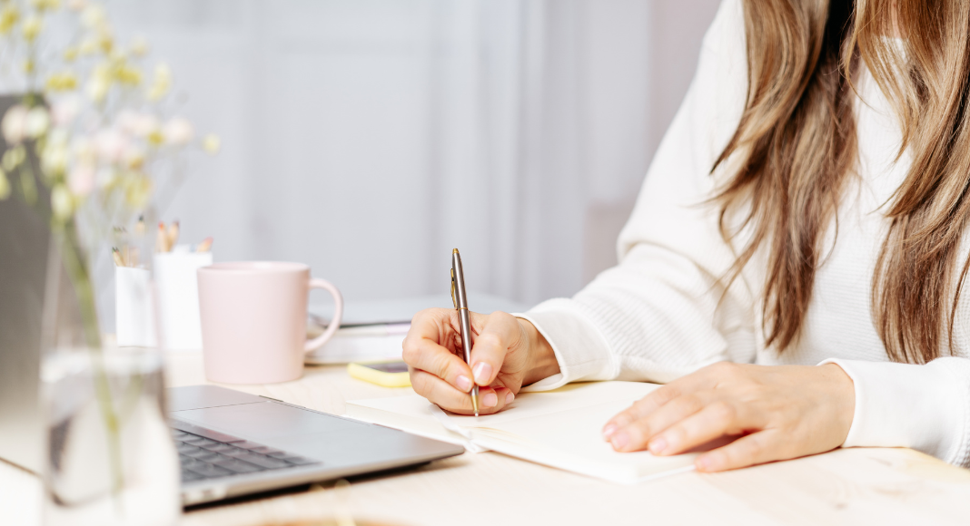 A woman sitting down to write a book.