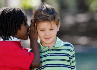 A boy whispering in a friend's ear.