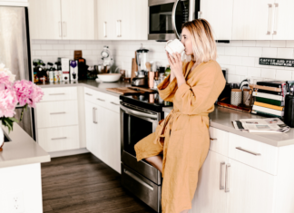 A woman drinking her first cup of morning coffee in the kitchen.