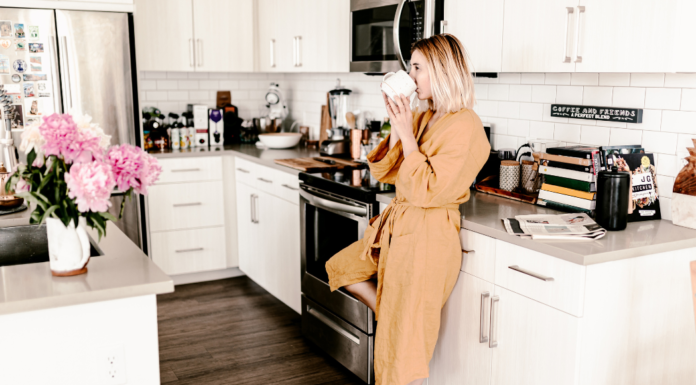 A woman drinking her first cup of morning coffee in the kitchen.