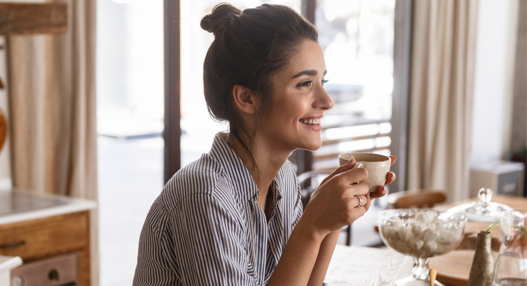 A woman pausing and enjoying a cup of coffee.