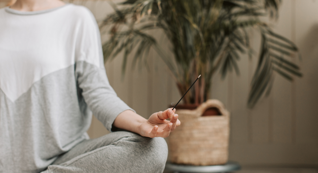 A woman meditating holding incense. 