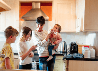 A mom with three kids of different ages in the kitchen.