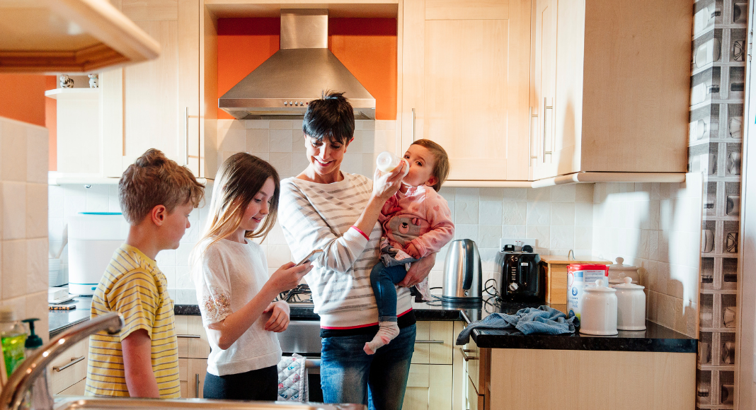 A mom with three kids of different ages in the kitchen.
