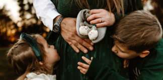 A Third Time Mom’s Secret to What Your Really Need for Your Newborn A family holding a pregnant mom's belly.