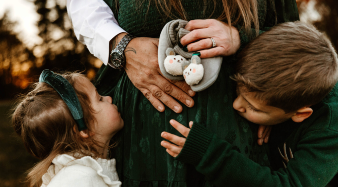 A Third Time Mom’s Secret to What Your Really Need for Your Newborn A family holding a pregnant mom's belly.