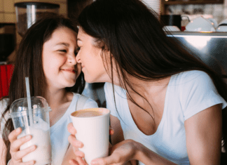 A mom and daughter having a milkshake together.