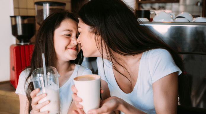 A mom and daughter having a milkshake together.