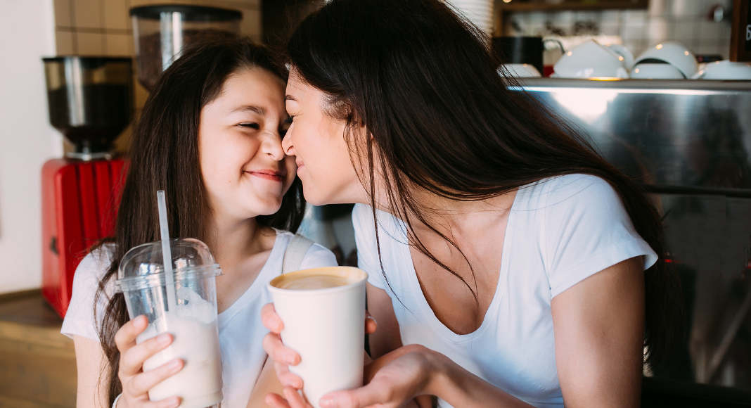 A mom and daughter having a milkshake together.